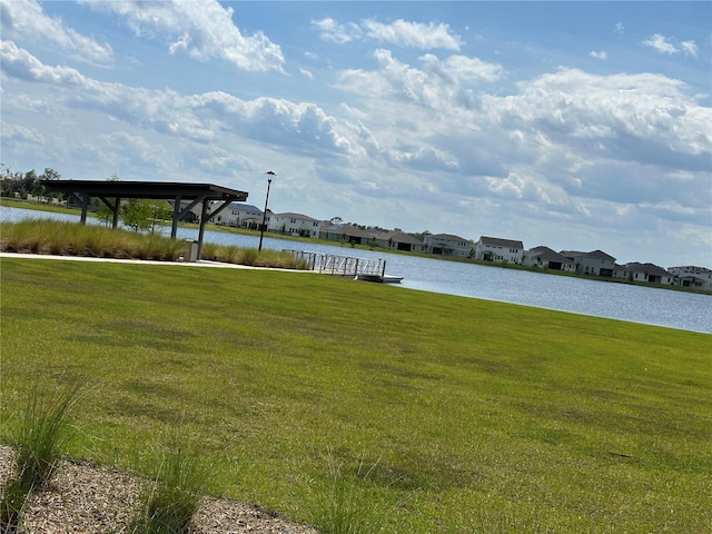 dock area with a lawn, a water view, and a residential view