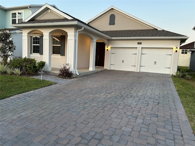 view of front of home featuring a garage, decorative driveway, and stucco siding