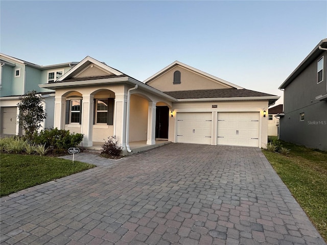 view of front of home with an attached garage, a front lawn, decorative driveway, and stucco siding