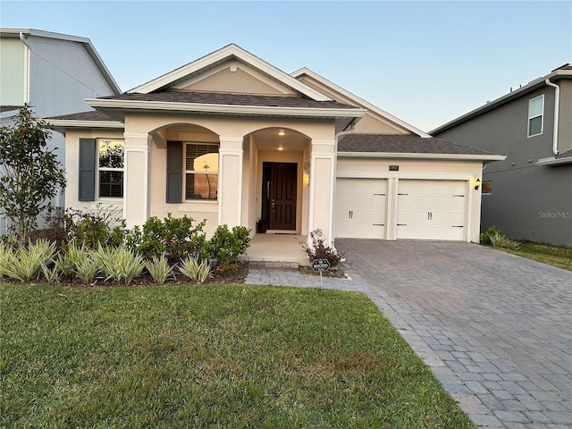 view of front of home with a front yard, an attached garage, and stucco siding