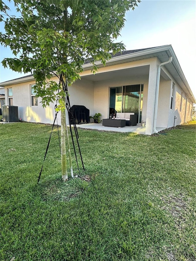 rear view of property featuring a patio area, a lawn, and stucco siding