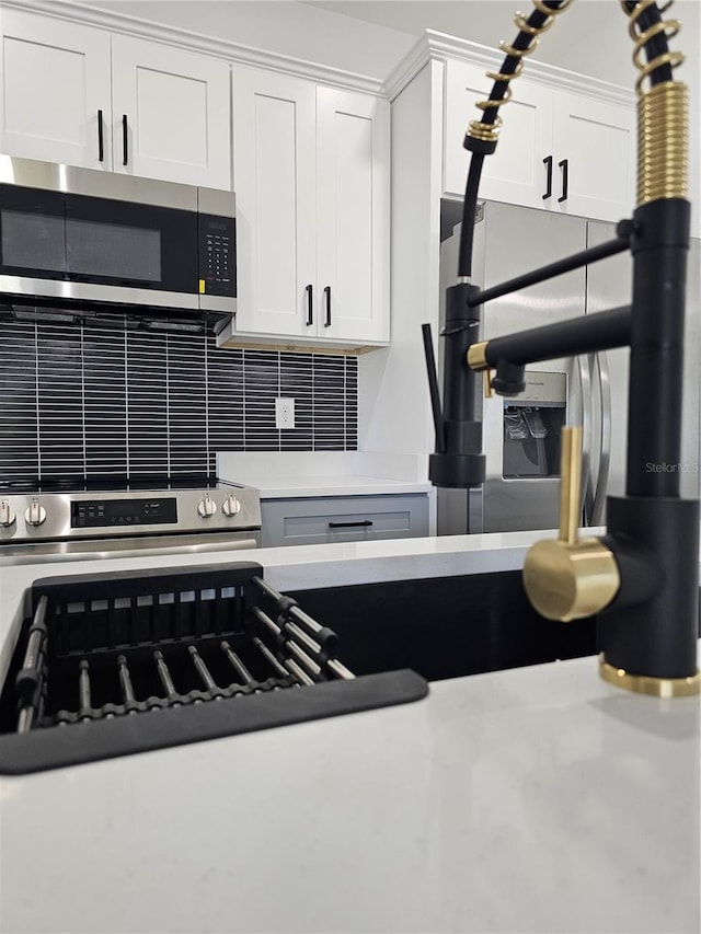 8249 Dimstead St, Port Charlotte, FL 33981 - kitchen featuring stainless steel appliances, decorative backsplash, white cabinetry, and light countertops