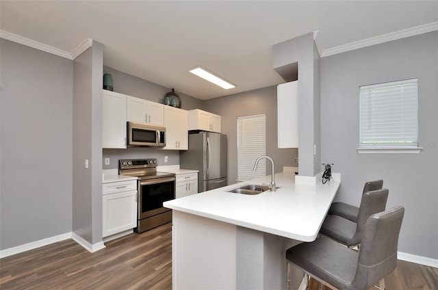 kitchen with white cabinetry, sink, stainless steel appliances, a kitchen breakfast bar, and kitchen peninsula