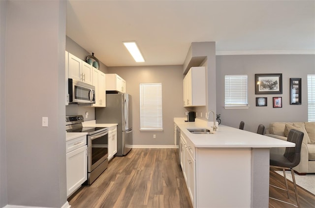 kitchen featuring white cabinets, appliances with stainless steel finishes, a breakfast bar area, and sink