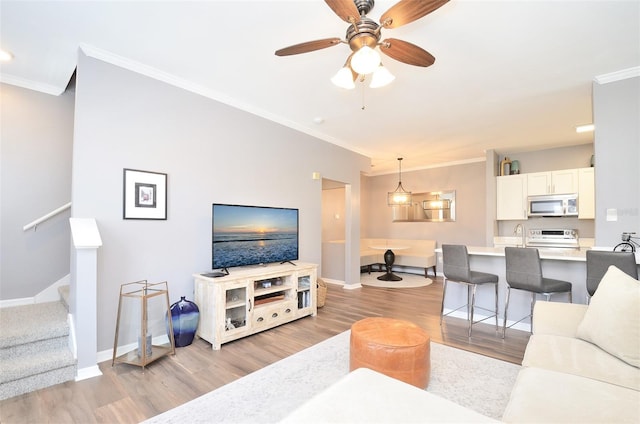 living room with light hardwood / wood-style flooring, ceiling fan, and crown molding