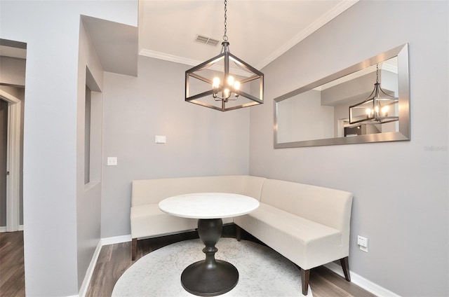 sitting room with breakfast area, dark wood-type flooring, crown molding, and a notable chandelier