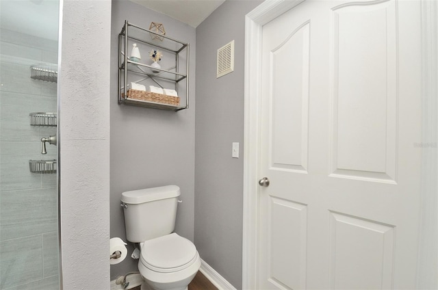 bathroom featuring a tile shower and toilet