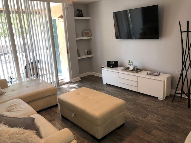 living room with built in shelves and dark wood-type flooring