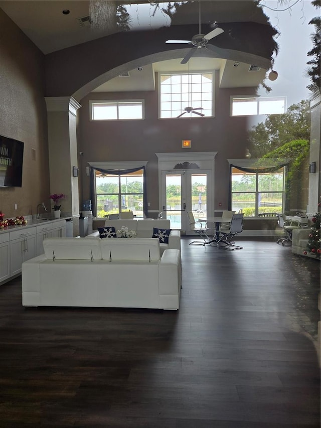 unfurnished living room featuring ceiling fan, sink, a high ceiling, and french doors