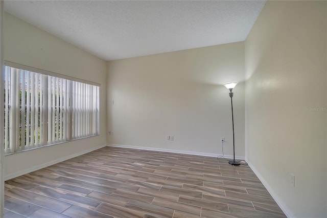 unfurnished room featuring a textured ceiling and light wood-type flooring