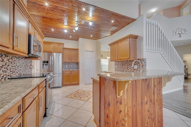 kitchen with light brown cabinetry, tasteful backsplash, a kitchen bar, wood ceiling, and stainless steel appliances