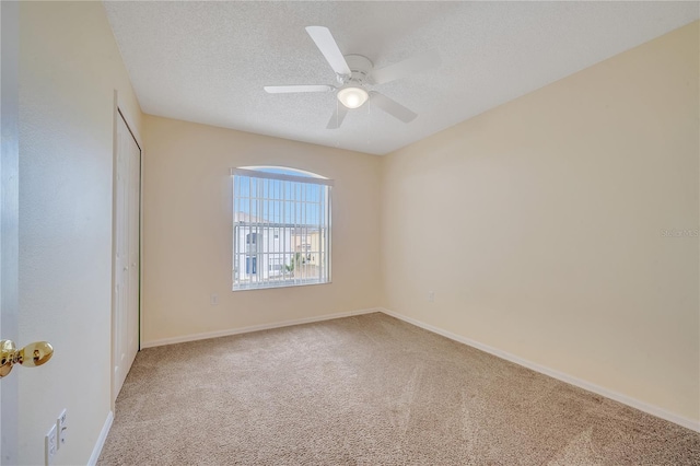 carpeted empty room with ceiling fan and a textured ceiling