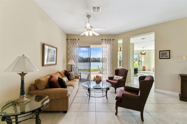 living room with a water view, ceiling fan, and light tile patterned flooring