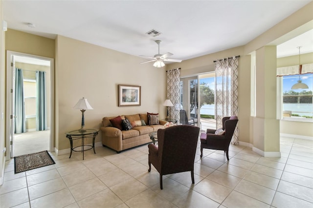 tiled living room featuring a water view and ceiling fan