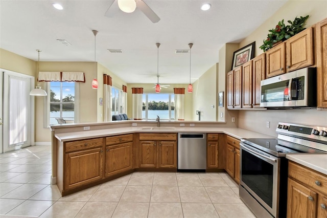 kitchen with kitchen peninsula, pendant lighting, stainless steel appliances, and sink