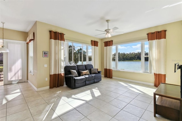 living room with ceiling fan, a water view, and light tile patterned floors