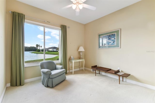 sitting room with carpet floors, a water view, and ceiling fan