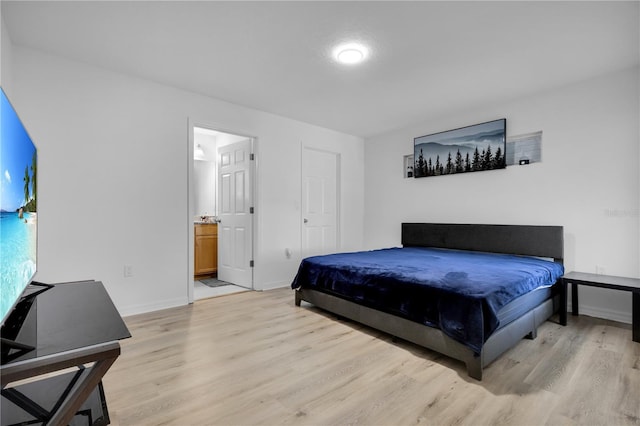 bedroom with light wood-type flooring and ensuite bathroom