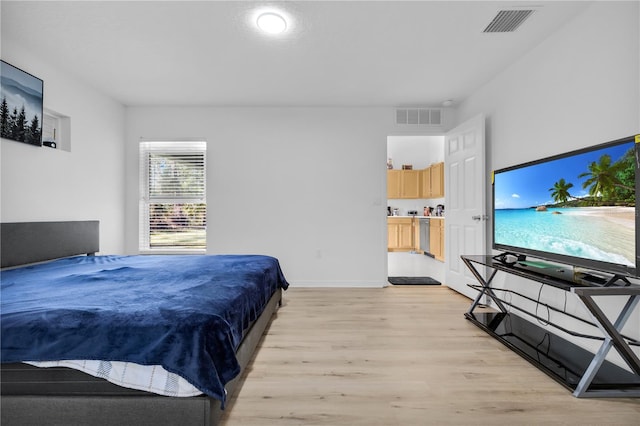 bedroom with light hardwood / wood-style floors and ensuite bathroom