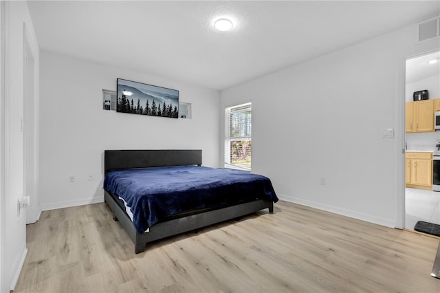 bedroom with ensuite bathroom and light hardwood / wood-style floors