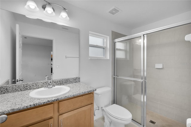 bathroom featuring an enclosed shower, vanity, and toilet