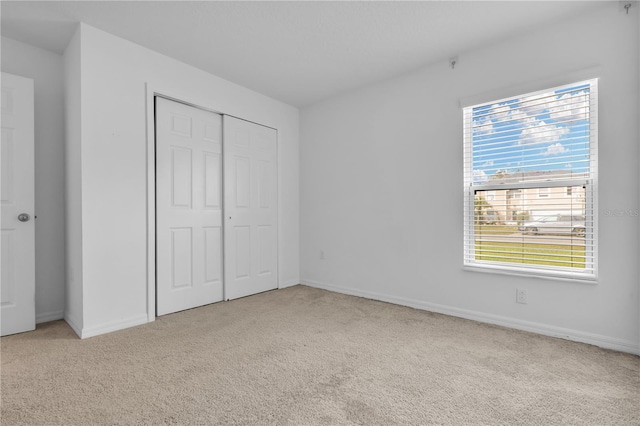 unfurnished bedroom with light colored carpet and a closet