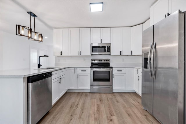 kitchen featuring sink, white cabinets, stainless steel appliances, and decorative light fixtures