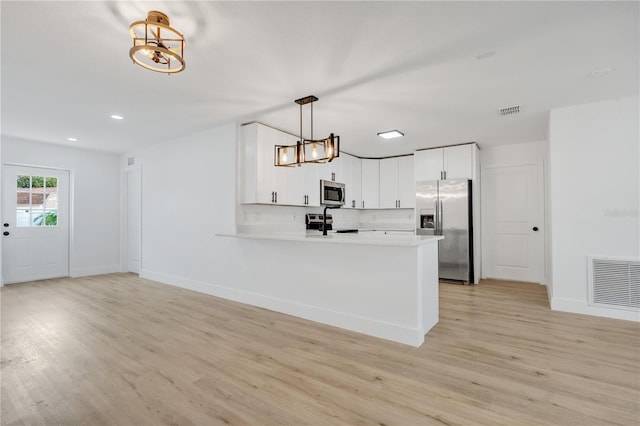 kitchen featuring white cabinetry, kitchen peninsula, decorative light fixtures, appliances with stainless steel finishes, and light wood-type flooring