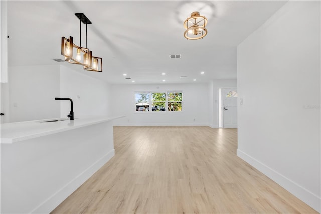 unfurnished living room with sink and light hardwood / wood-style floors