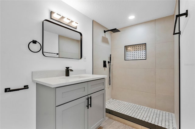 bathroom featuring a tile shower, vanity, and a textured ceiling