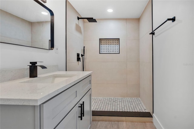 bathroom with vanity, wood-type flooring, and tiled shower