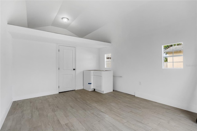 unfurnished room featuring a healthy amount of sunlight, light hardwood / wood-style floors, and vaulted ceiling