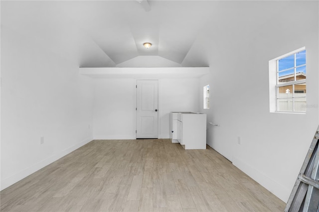 unfurnished room featuring lofted ceiling, a healthy amount of sunlight, and light wood-type flooring