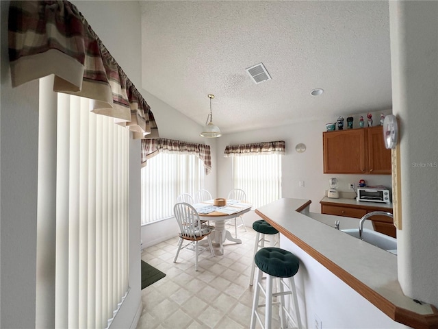 kitchen with a kitchen breakfast bar, a textured ceiling, hanging light fixtures, and lofted ceiling