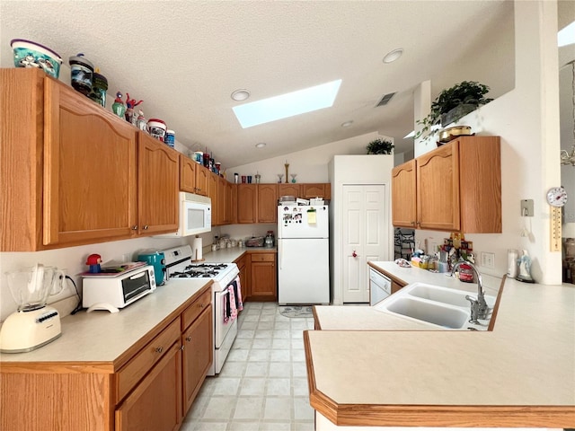 kitchen featuring kitchen peninsula, a textured ceiling, white appliances, lofted ceiling with skylight, and sink