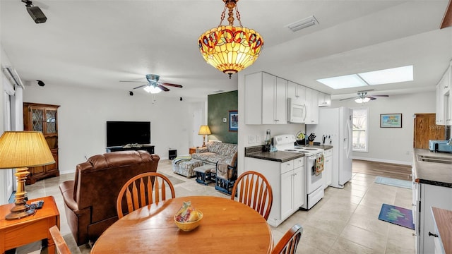 kitchen featuring white cabinetry, white appliances, light tile patterned floors, and a skylight