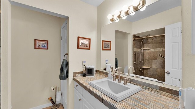 bathroom with a tile shower and vanity