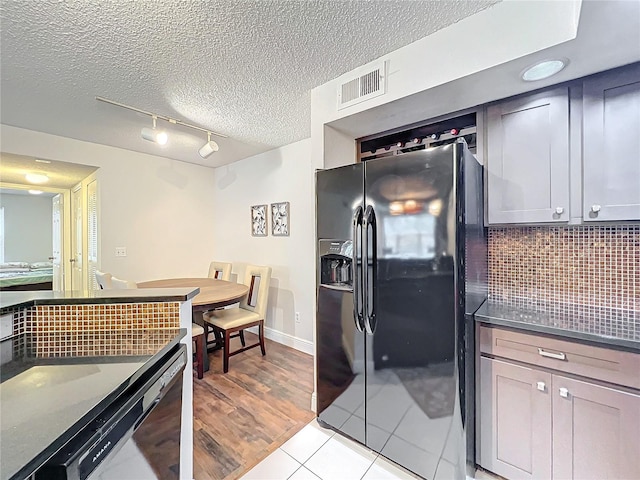 kitchen featuring backsplash, black refrigerator with ice dispenser, a textured ceiling, dishwasher, and light tile patterned flooring