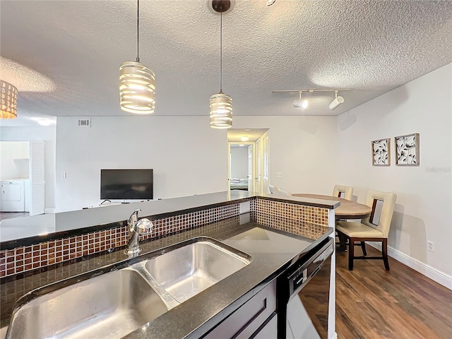 kitchen featuring dishwasher, a textured ceiling, washer / clothes dryer, and sink