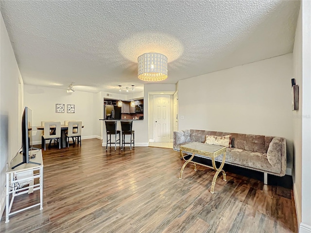 living room featuring dark hardwood / wood-style floors, a textured ceiling, and a chandelier