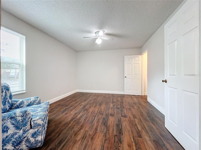 empty room with dark hardwood / wood-style floors, ceiling fan, and a textured ceiling