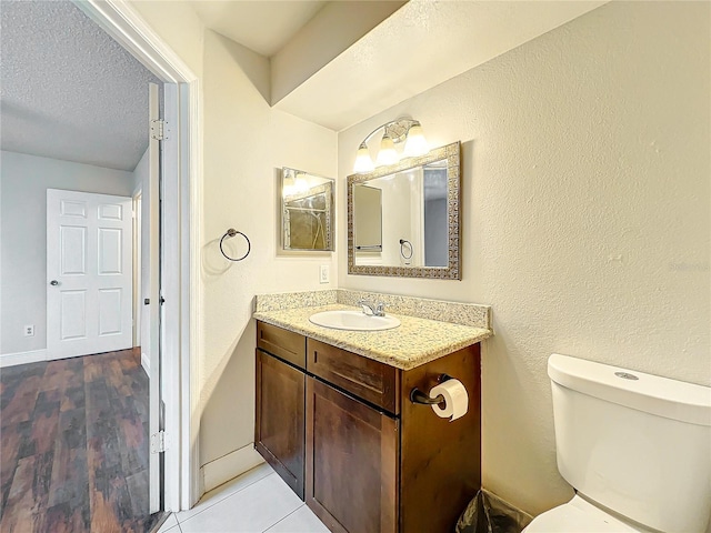 bathroom featuring tile patterned floors, vanity, toilet, and a textured ceiling