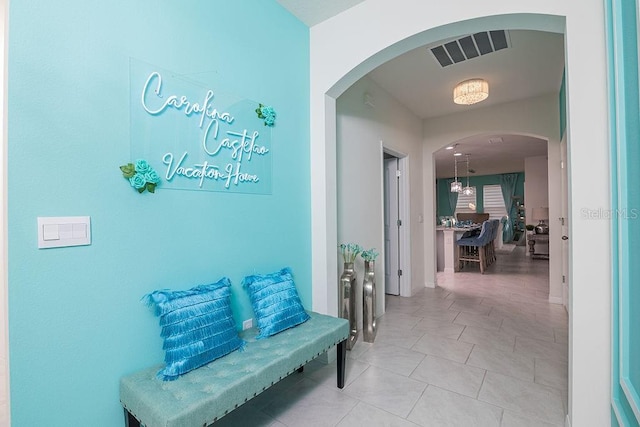 corridor with tile patterned flooring and a notable chandelier