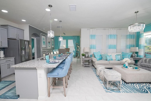 kitchen with stainless steel fridge with ice dispenser, decorative light fixtures, a kitchen island with sink, and a kitchen breakfast bar