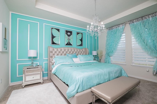 bedroom featuring carpet floors, a tray ceiling, and a notable chandelier