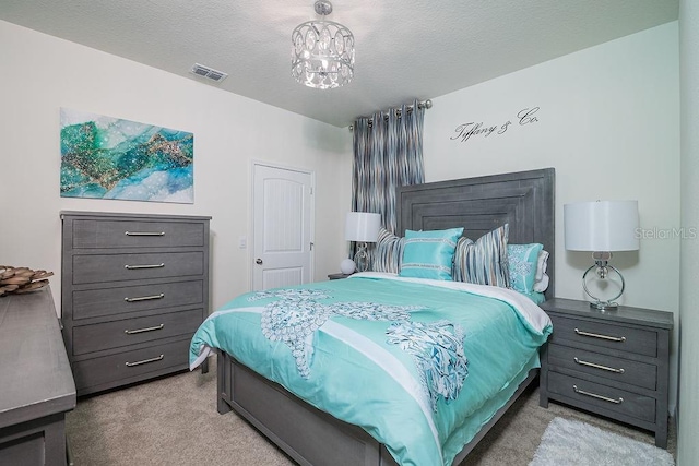 bedroom featuring light carpet, a textured ceiling, and a notable chandelier