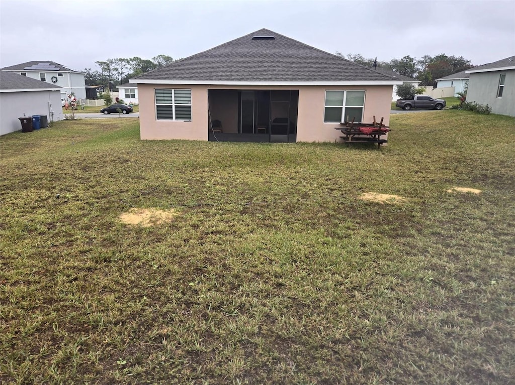 rear view of property with a lawn and a sunroom