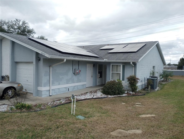 view of front of home with central air condition unit, a front yard, and solar panels