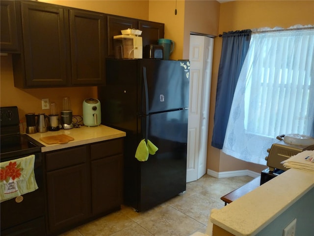 kitchen with dark brown cabinets, light tile patterned floors, and black appliances