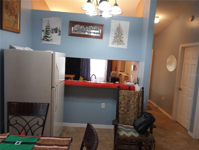 kitchen with an inviting chandelier, white refrigerator, sink, vaulted ceiling, and tile patterned flooring